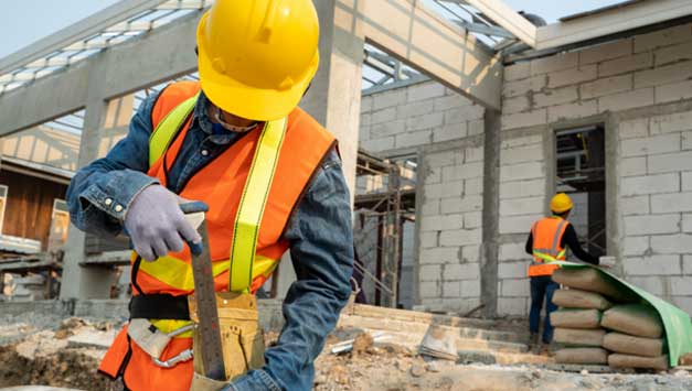 A construction worker pulls a tool from his toolbelt.