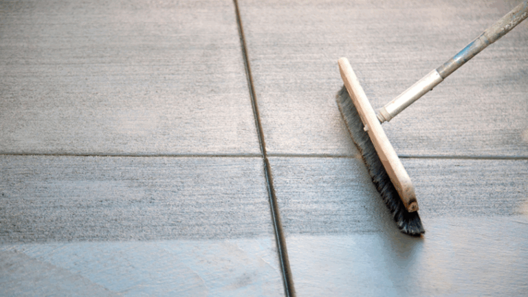 A broom runs across a freshly laid cement to give it texture.