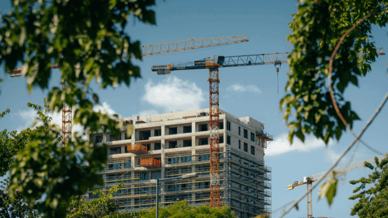 A view of a building in the process of construction with trees in the foreground.