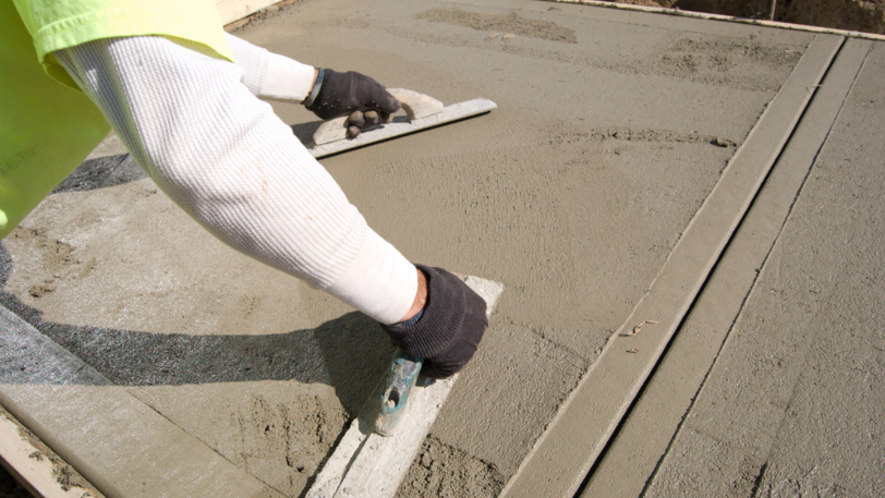 A concrete worker smooths a slab using specialized tools from Stevenson Supply.