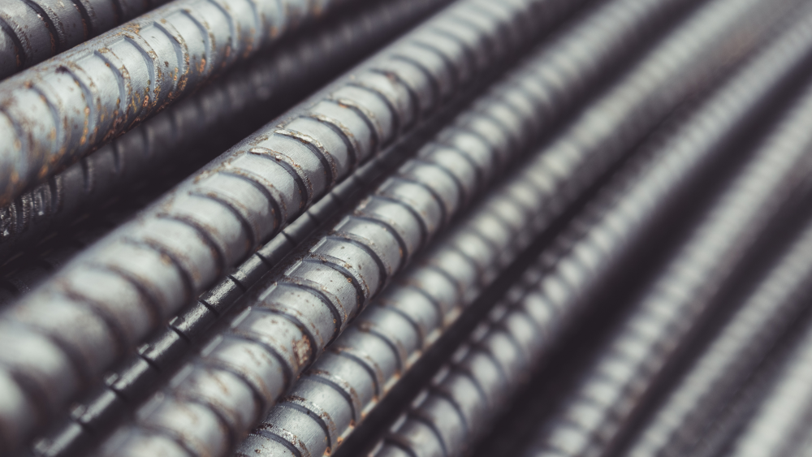 A close up image of a stack of silver colored rebar with some minor blemishes.